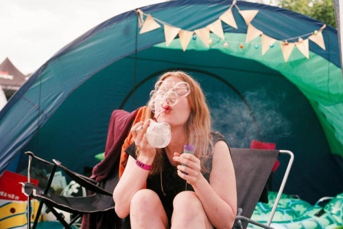 Een meisje is aan het bellenblazen voor haar tent op een muziekfestival terrein